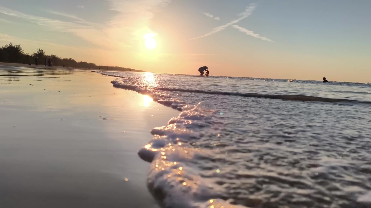 Ondas do Oceano Lavando a Praia Arenosa ao Pôr do Sol