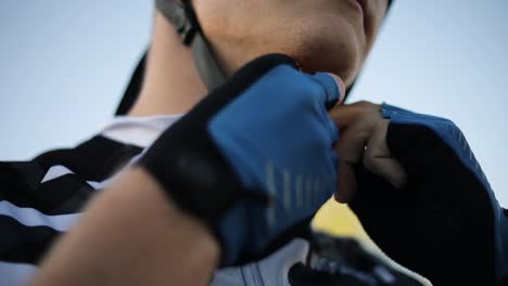 a man wearing sunglasses buckling up his bicycle helmet