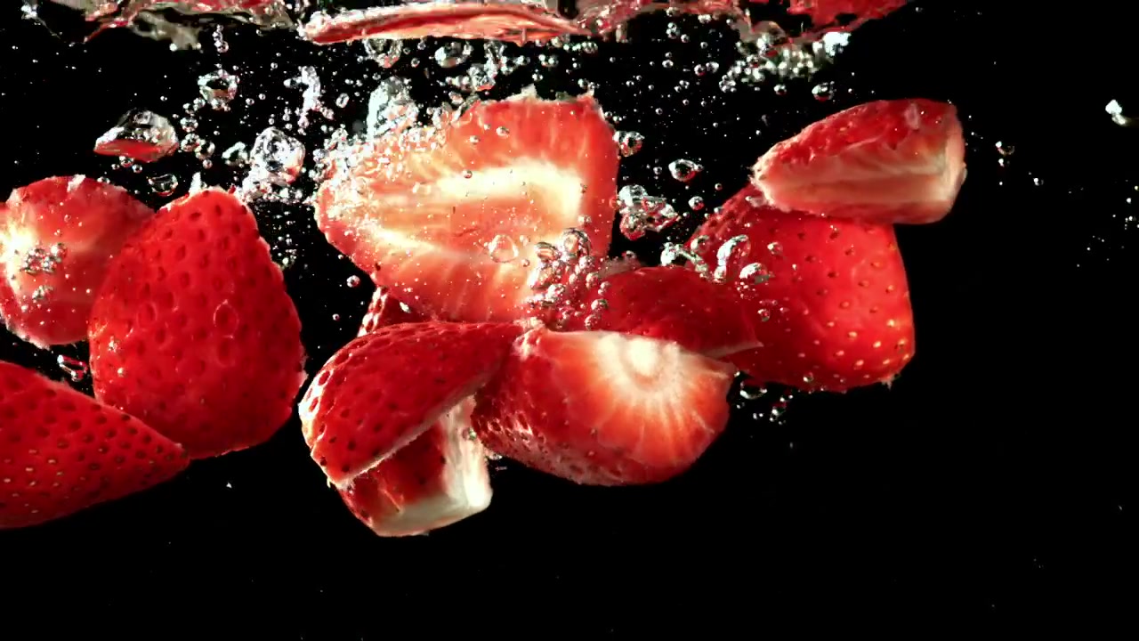 Fragole rosse fresche che schizzano nell'acqua al rallentatore