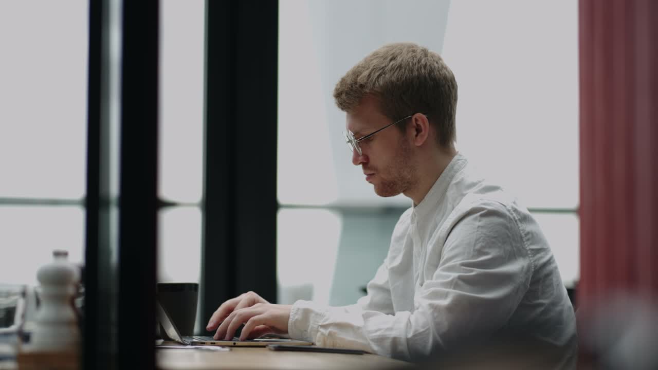 freelance it specialist is working with laptop in cafe in daytime, portrait of man with notebook