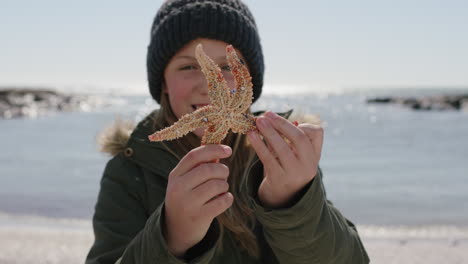 portrait of cute girl holding starfish on beach smiling cheerful