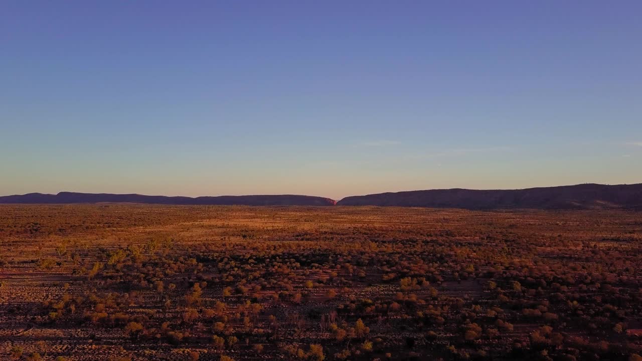 Sunset over the Central Australian Outback. Cinematic aerial track forwards + pedestal shot. Filmed on a DJI Mavic Pro on a camel farm near Alice Springs.