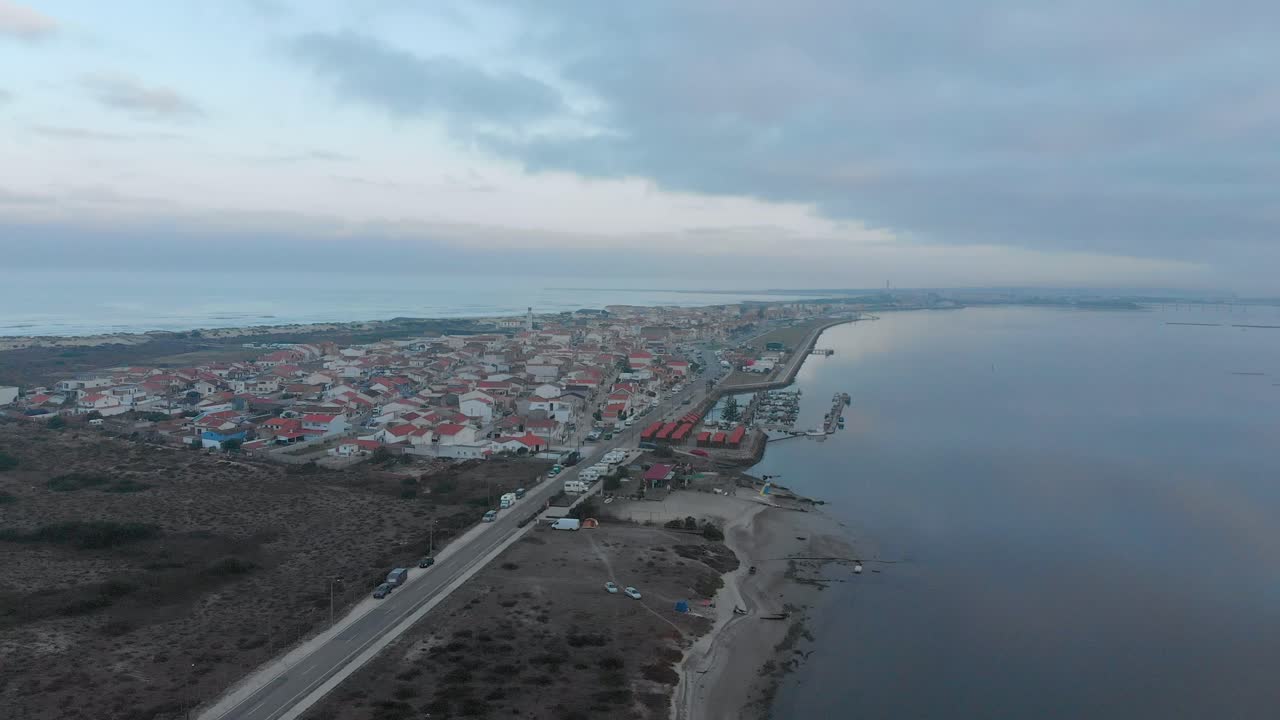 vista aérea de un pequeño pueblo entre el océano y el río en un día nublado