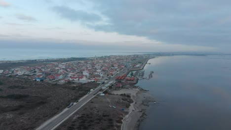 Vista-Aérea-De-Un-Pequeño-Pueblo-Entre-El-Océano-Y-El-Río-En-Un-Día-Nublado