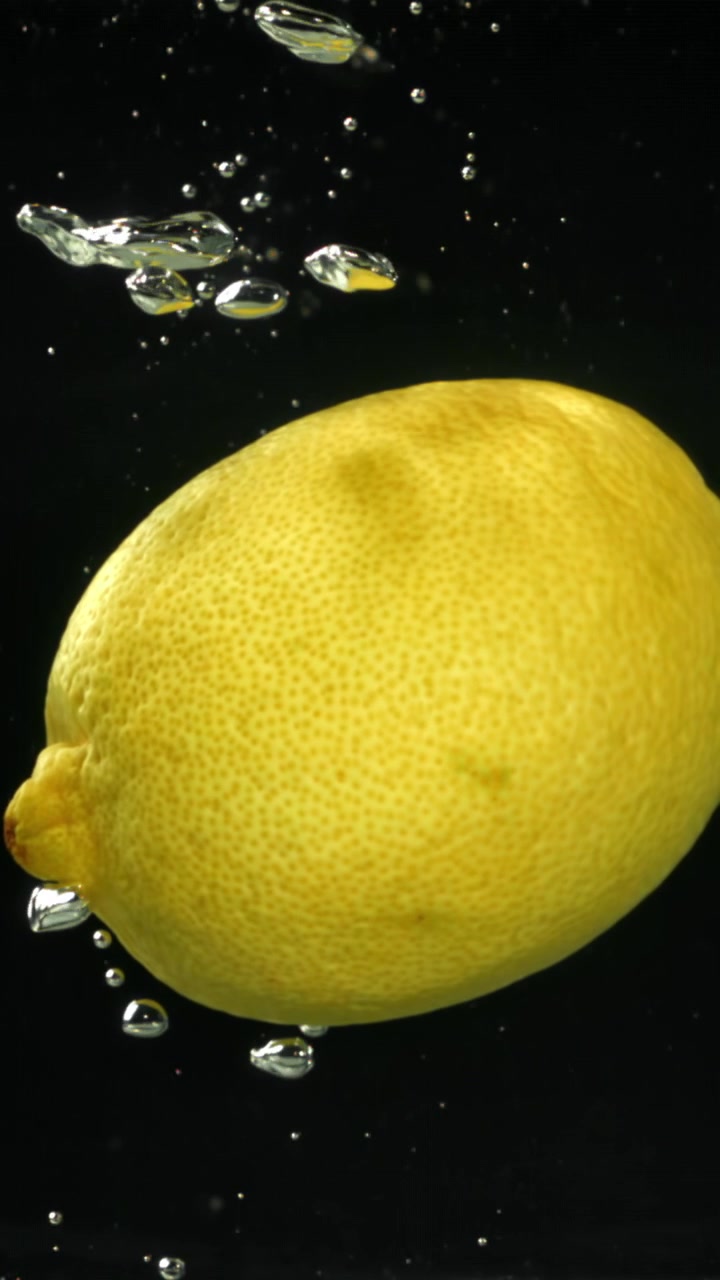 Al rallentatore di un limone sommerso nell'acqua con bolle