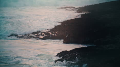 stormy sea hitting rocky coastline in evening. powerful waves rolling breaking