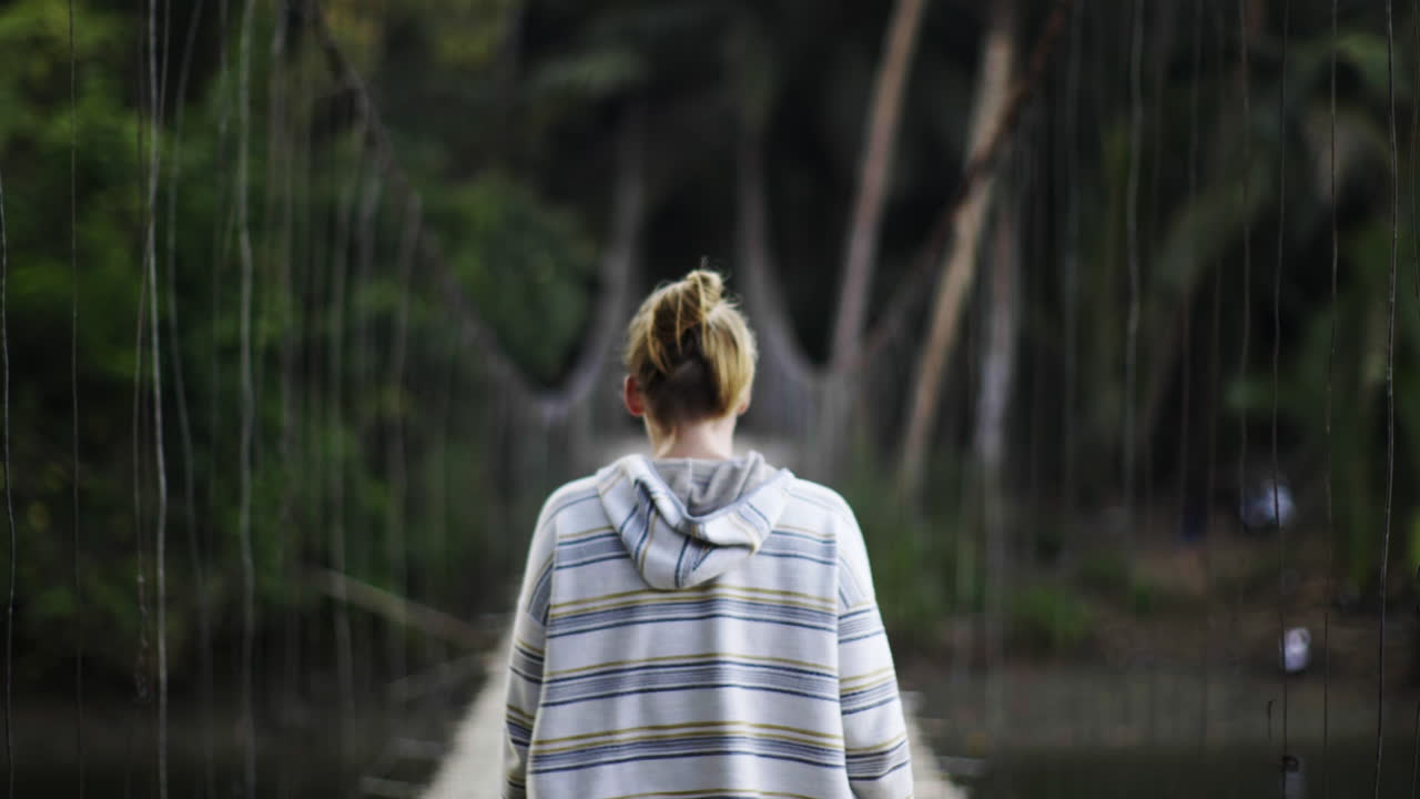 Woman Walking on a Suspension Bridge in a Forest