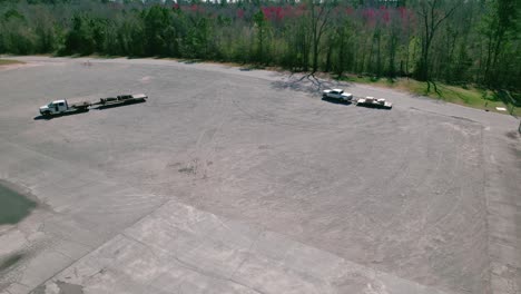 Two-white-pickup-trucks-in-a-large-empty-parking