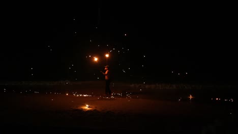 un artista muestra habilidades de fuego en una playa.