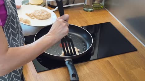 una mujer cocinando galletas de pollo.