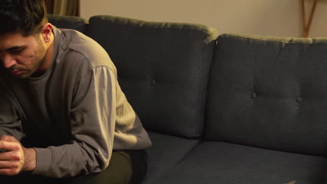 young man spending evening at home sitting on sofa with mobile phone scrolling through internet or social media 12