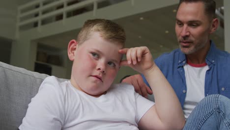 Padre-Caucásico-Sonriente-Hablando-Con-Su-Triste-Hijo-Y-Sentado-En-La-Sala-De-Estar