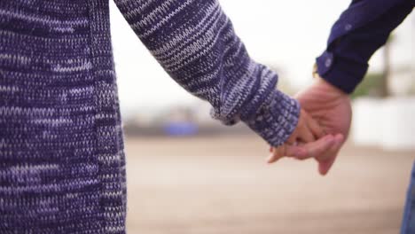 vista de cerca de una joven pareja en la playa tomados de la mano y caminando juntos. disparo en cámara lenta