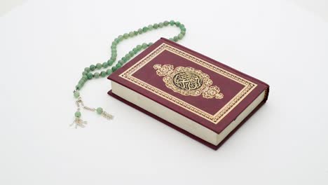 4k islamic holy book with rosary on a turnable white background, translation is quran kareem in arabic