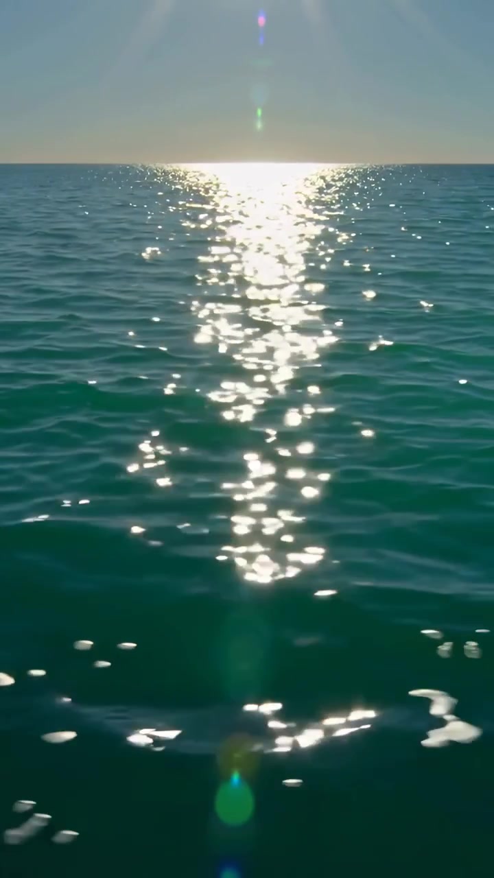 Vertical video: Shining low sun glare column shifting on sea, wind ripples scattering sparkles