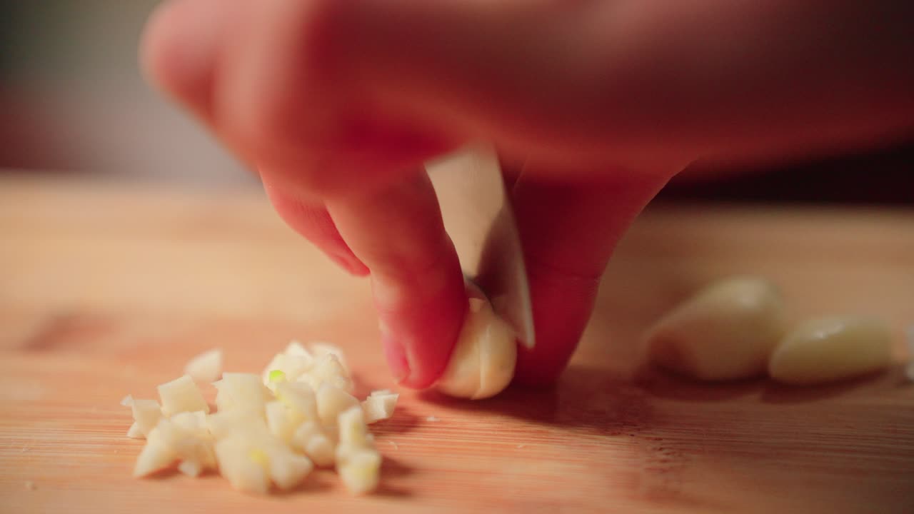 Cutting garlic by hand with a knife on a cutting board