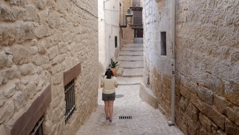 woman exploring narrow stone alley in valderrobres, spain on a sunny afternoon