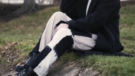 mujer joven con un abrigo negro sentada en un parque en otoño por la tarde en un mar