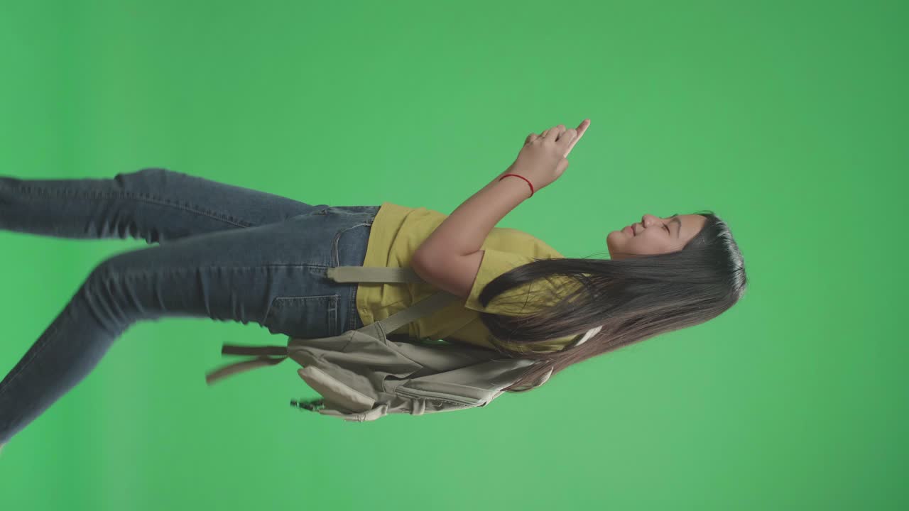 Side View Of Asian Girl Student Playing Game On Mobile Phone And Walking To School On Green Screen Chroma Key