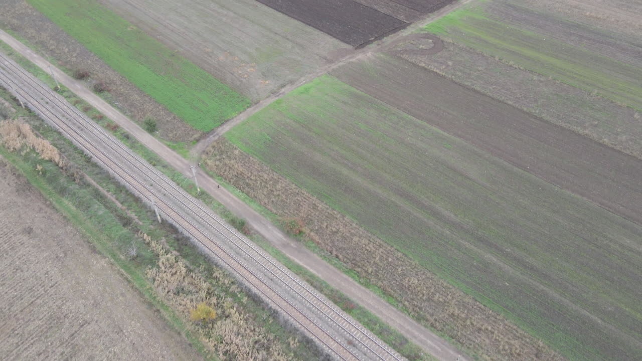 la antena del dron se inclina hacia arriba sobre los campos de cultivo desnudos marrones para revelar el cielo nublado