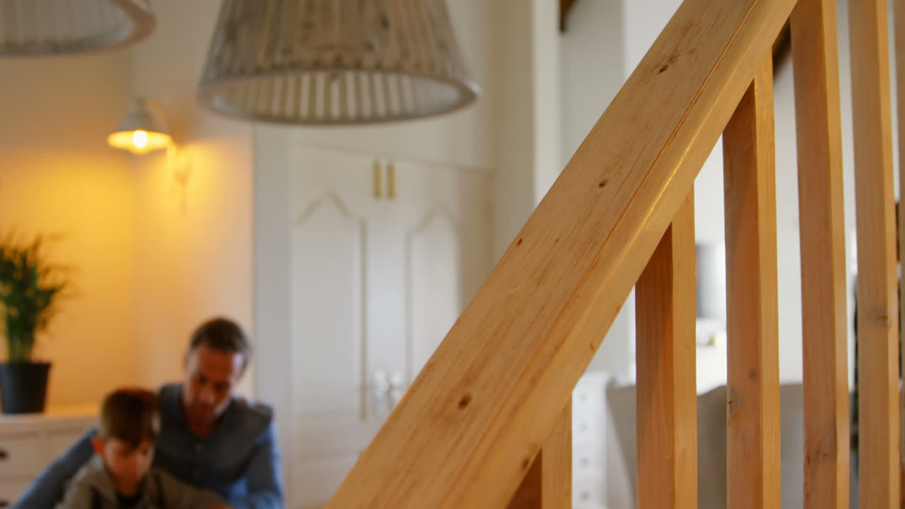 фронтальный вид молодого белого отца, помогающего сыну с домашним заданием в комфортном доме 4k