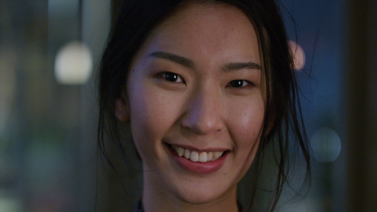 밤에 도시에서 행복하게 미소 짓는 아름다운 아시아 여성의 초상화