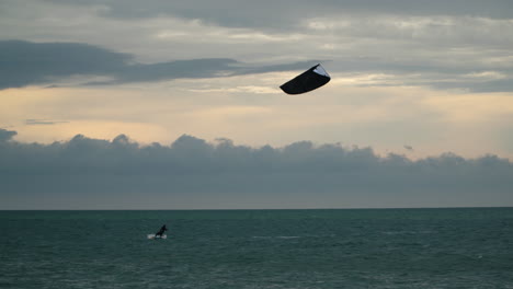 Silhouette-Eines-Sportlers,-Der-Beim-Kitesurfen-Bei-Sonnenuntergang-Vor-Der-Dramatischen,-Farbenfrohen-Skyline-Springt---Weitwinkelstatik