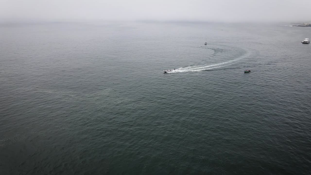 tiro de drone de una persona haciendo wakeboard en el océano en un bote en lima perú