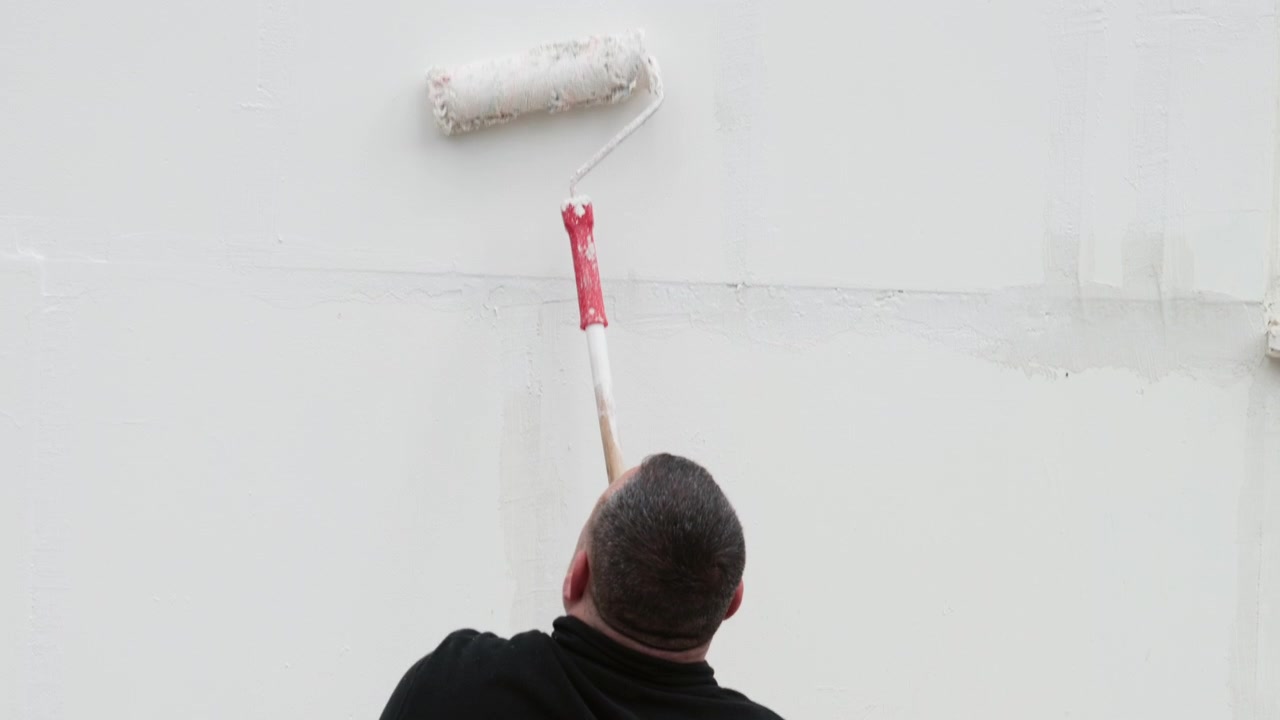Rullo da imbianchino che stende pittura bianca su una parete.