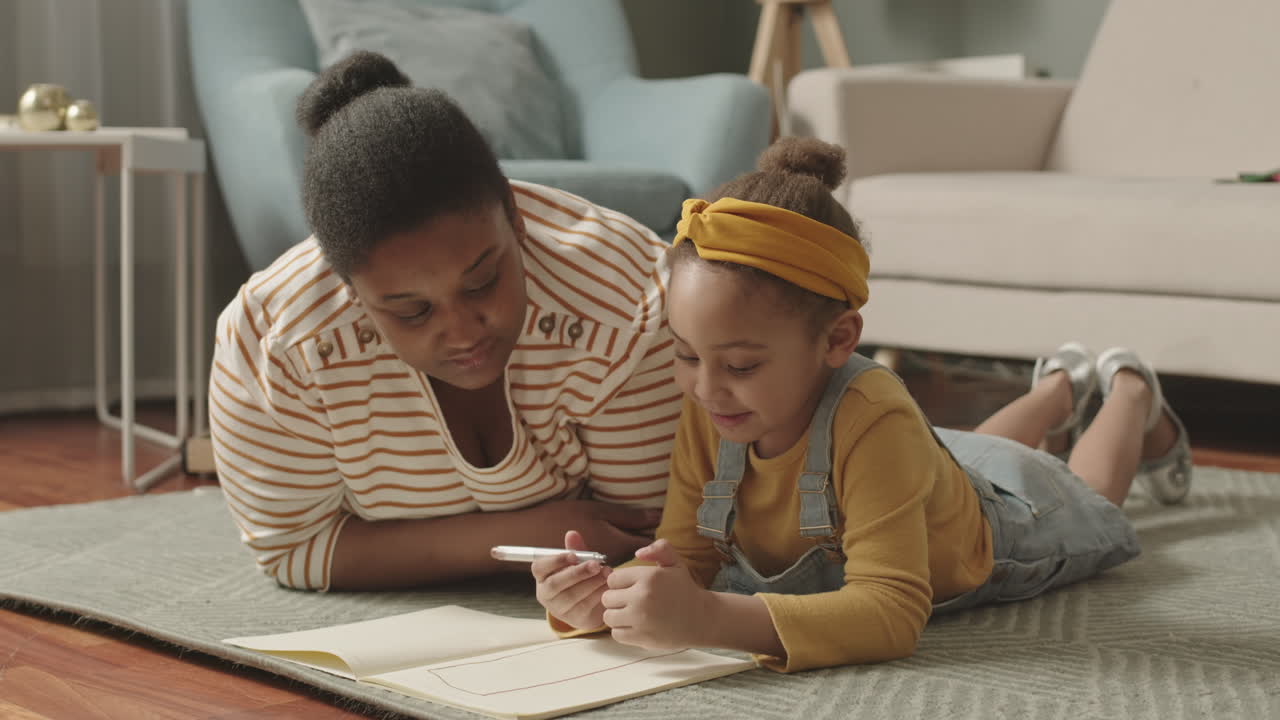 African Woman Watching Her Little Daughter Drawing