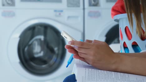 mujer usando teléfono móvil en la lavandería 4k