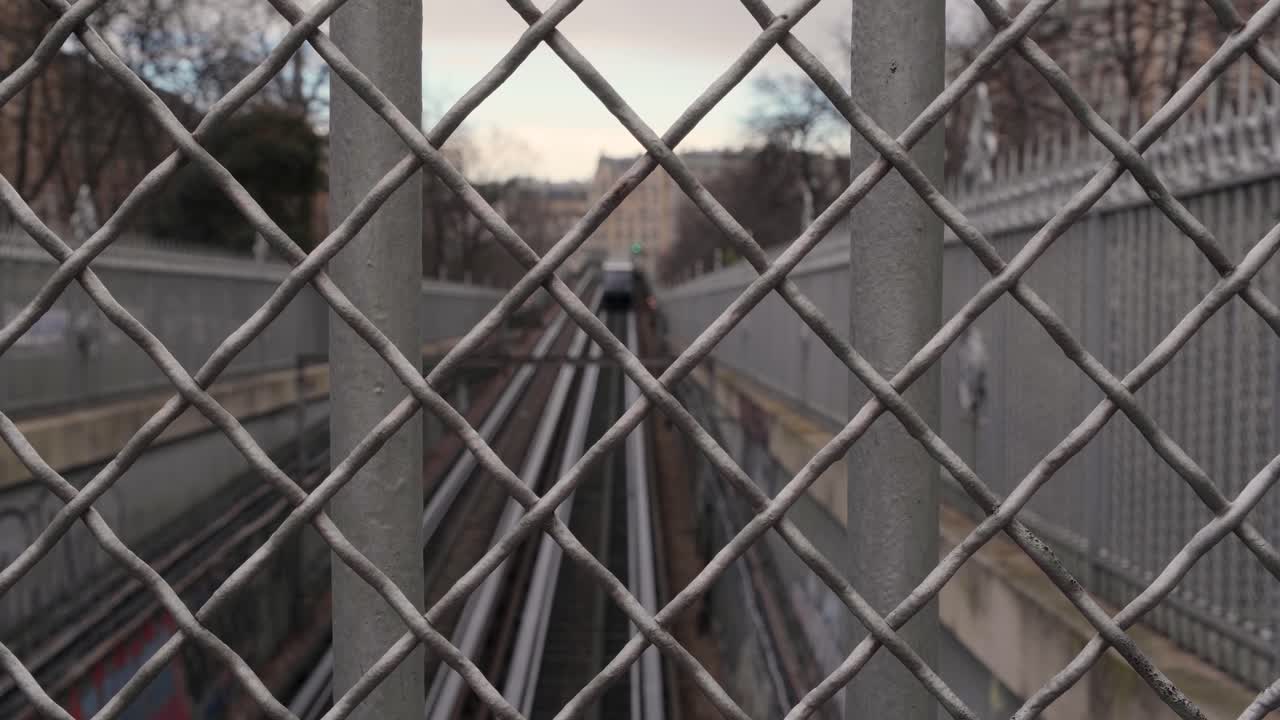 Parisian metro exiting a tunnel filmed behind a fence