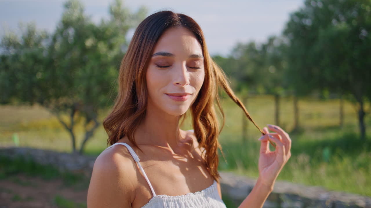 Girl enjoy sunshine looking camera at nature closeup. Woman playing with hair