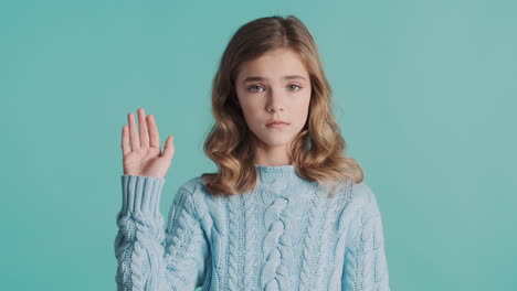 teenage caucasian girl sadly waving goodbye and looking at the camera.