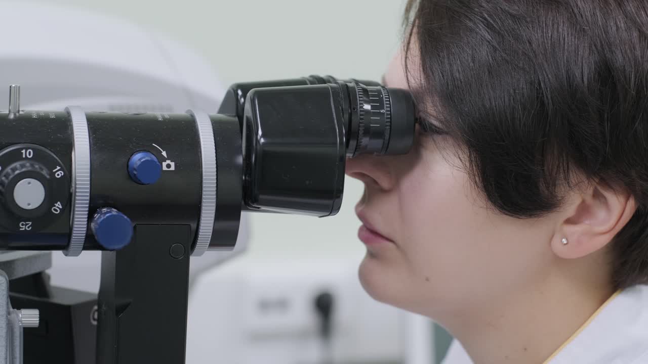 여성 의사는 안과 클리닉에서 환자의 눈을 안경으로 보고 있습니다. 시력의 전문적인 검사