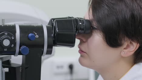 la mujer está viendo a través del oftalmoscopio en los ojos del paciente en la clínica oftalmológica. inspección profesional de la visión
