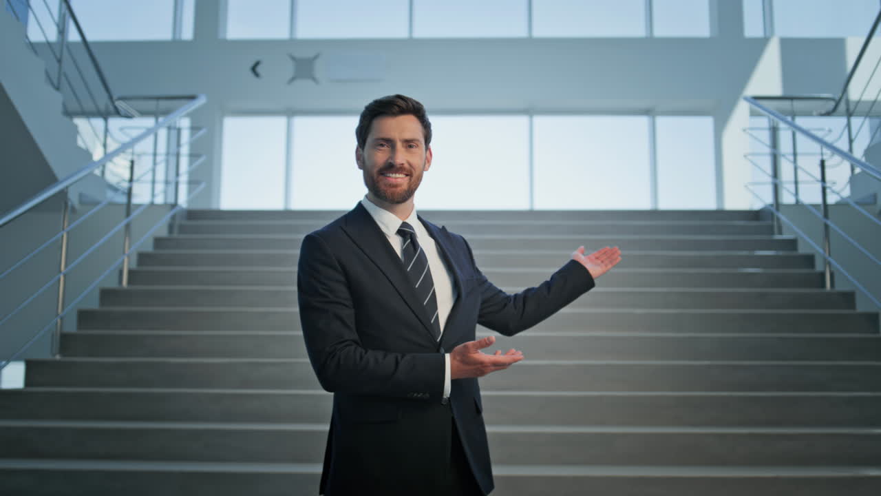 Smiling manager inviting office standing at staircase in elegant suit closeup