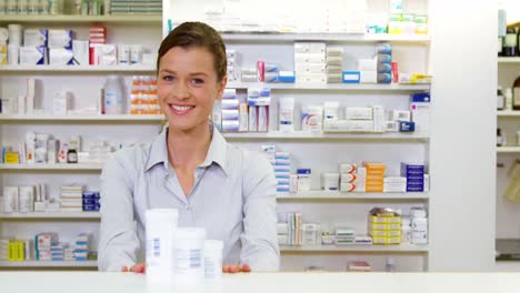farmacéutico sonriente sosteniendo un contenedor de medicamentos en la farmacia