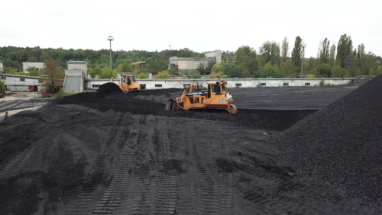 Bulldozer at coal warehouse. Tractor using for loading coal into trucks for further transport