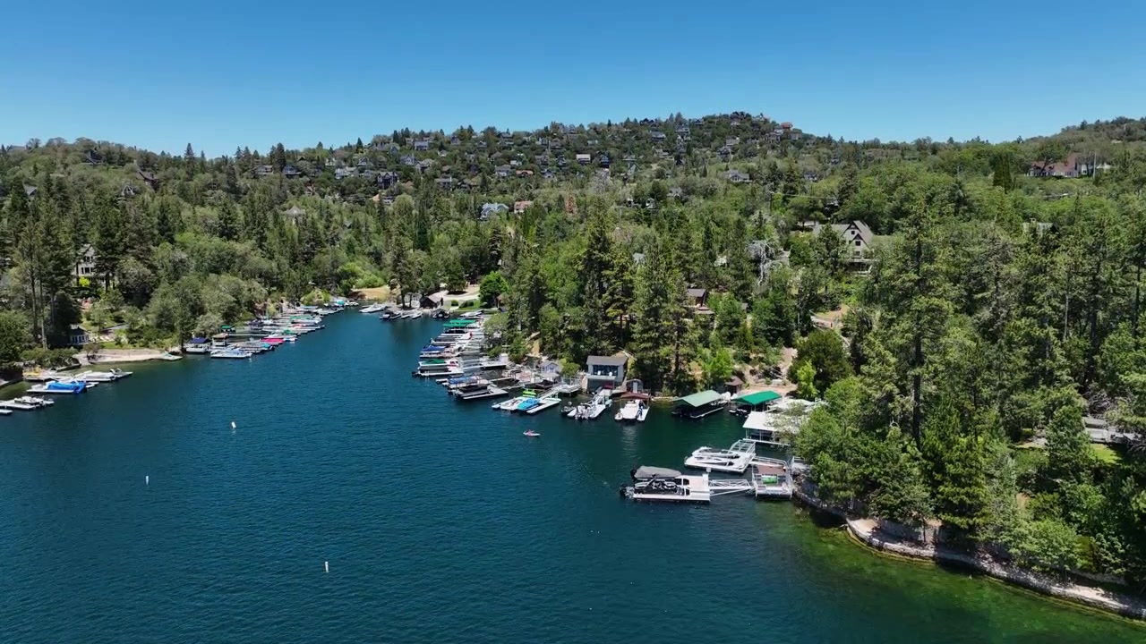 Drone che si alza davanti a moli privati per barche e ville sulle colline del Lago Arrowhead.