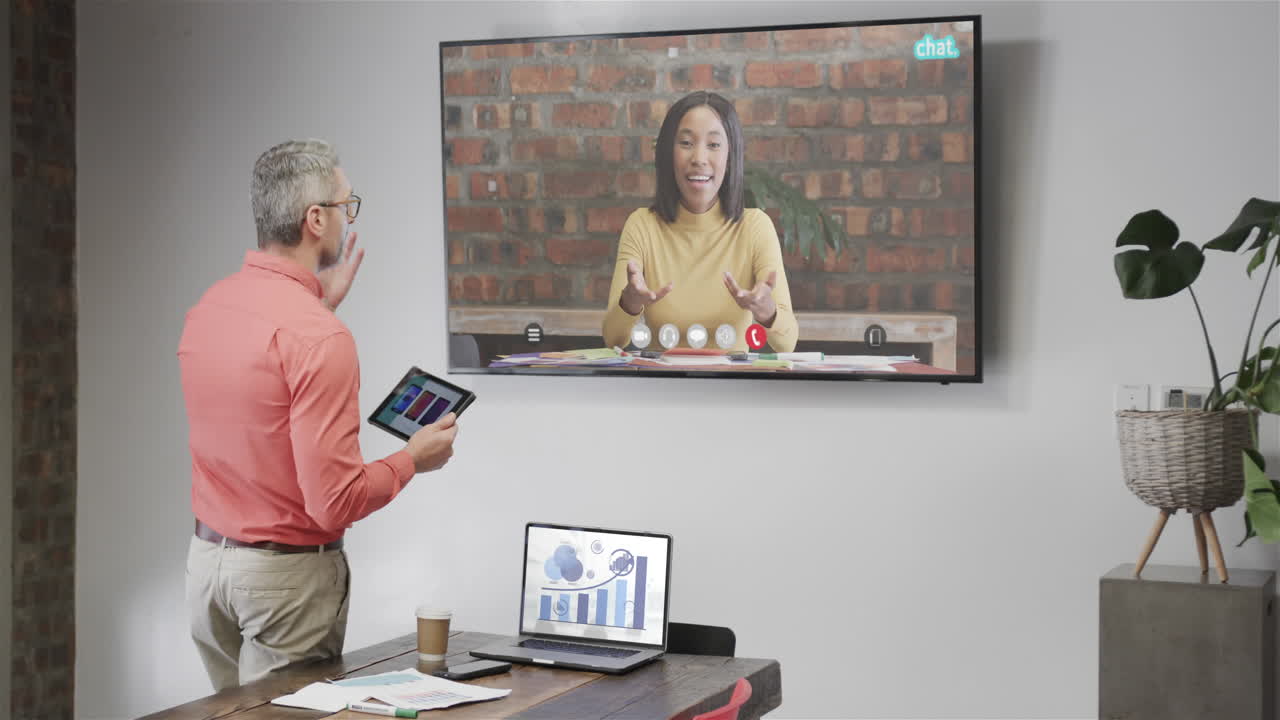 hombre de negocios caucásico en videollamada con una colega afroamericana en la pantalla de televisión