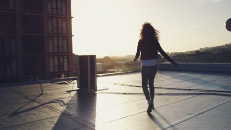 fashionable young woman on urban rooftop with arms outstretched