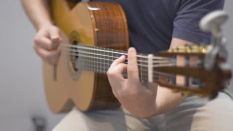 a professional guitarist playing on an acoustic guitar during a redording session in a studio with racking focus