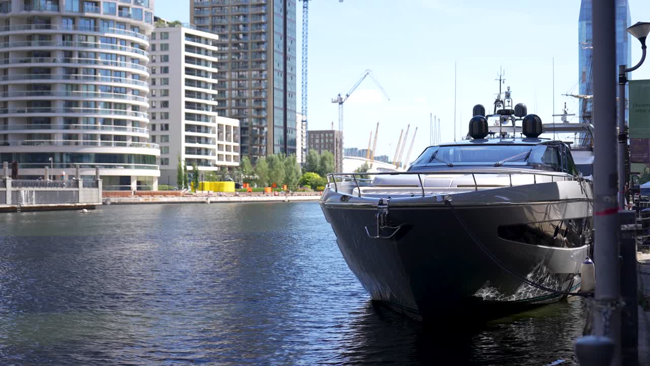 Grande imbarcazione di lusso ormeggiata lungo il canale a Canary Wharf, Londra, durante una soleggiata mattina estiva con i moderni edifici residenziali sullo sfondo