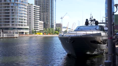 large luxury boat is docked on the side of the canal in canary wharf, london during a sunny summer morning with the modern apartment buildings in the background