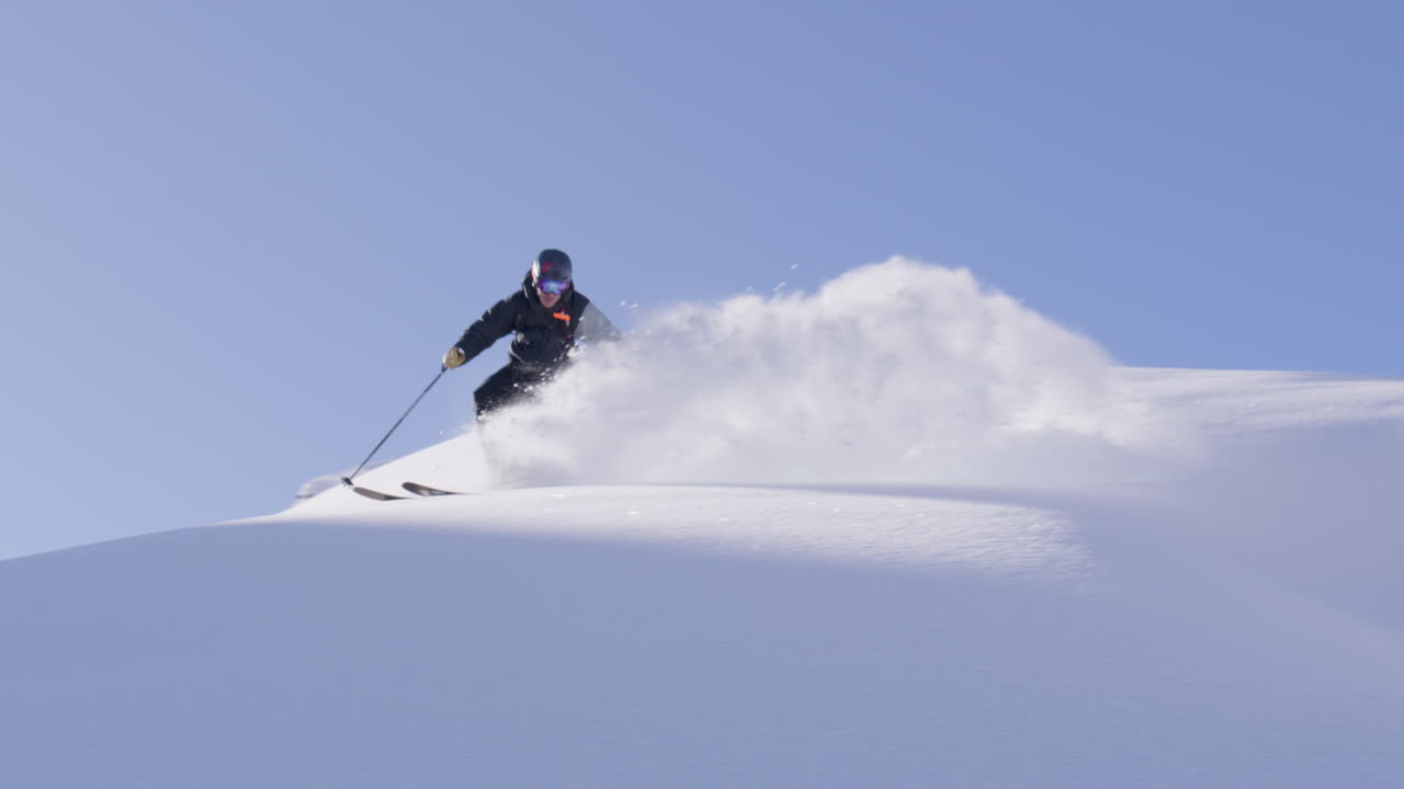 Freeride skier skinning up with Dents du Midi backdrop, then charging steep powder on a bluebird day near Champéry and Avoriaz.