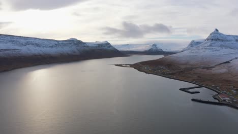 panorámica a través de magníficas montañas cubiertas de nieve que rodean el gran río westfjords, antena de drones