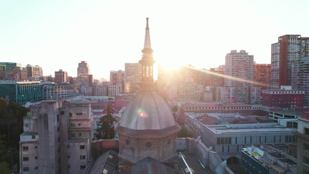 Veduta aerea che ruota attorno alla Cattedrale Metropolitana di Santiago con un tramonto splendente che si staglia dietro la guglia della cupola.