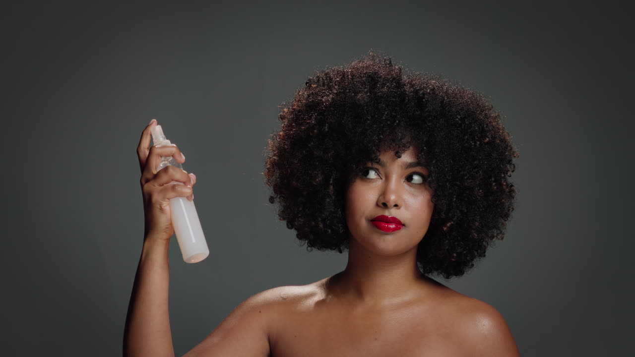 Woman applying hair spray to her afro