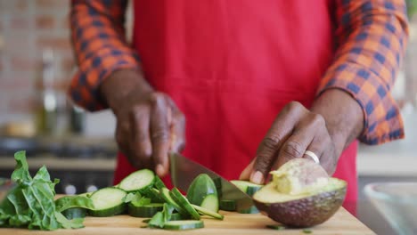 Hands-of-african-american-senior-man-cutting-vegetables